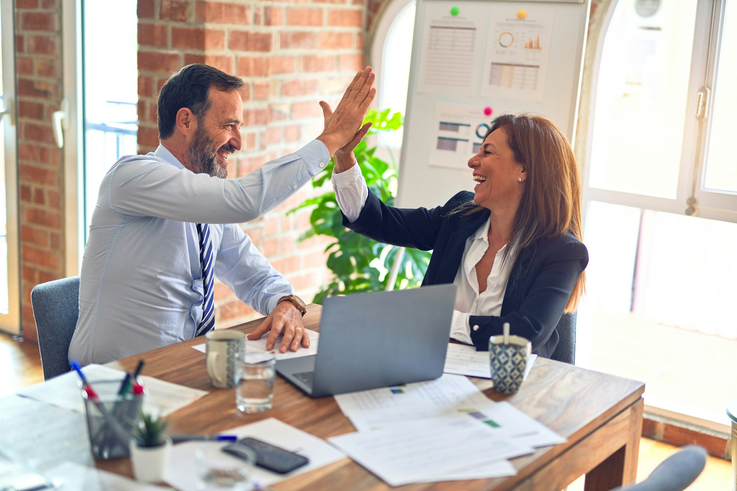 Two business partners celebrating at their desk